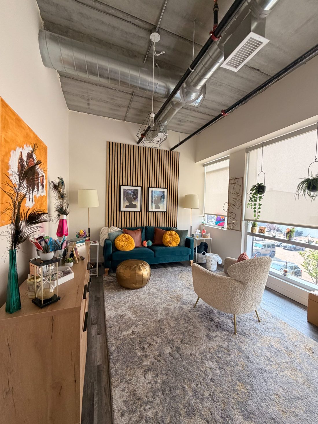 The Drop of Dew therapy room at Empowered Collective in Edmonton: a warm, light-filled space with a teal velvet sofa, a boucle armchair, artwork and plants